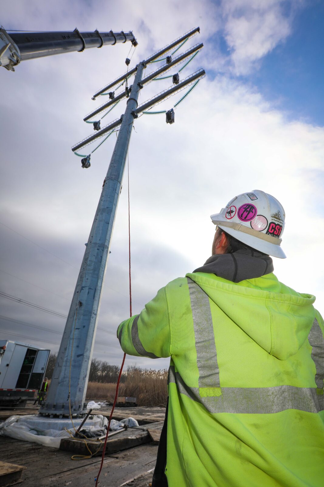 An L.E. Myers employee stands below a transmission pole at the Central East Energy Connect project.